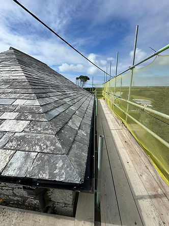 Slate roof fitted with safety netting overlooking open countryside
