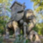 Stone elephant sculpture carrying a tower in the Park of the Monsters (Parco dei Mostri) in Bomarzo, surrounded by woodland.