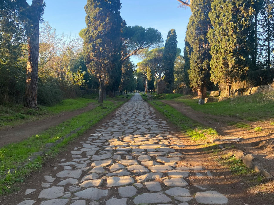 Stone-paved Appian Way lined with cypress trees near Villa dei Quintili in Rome.
