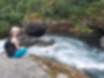 Ulrika sitting on a rock by a river