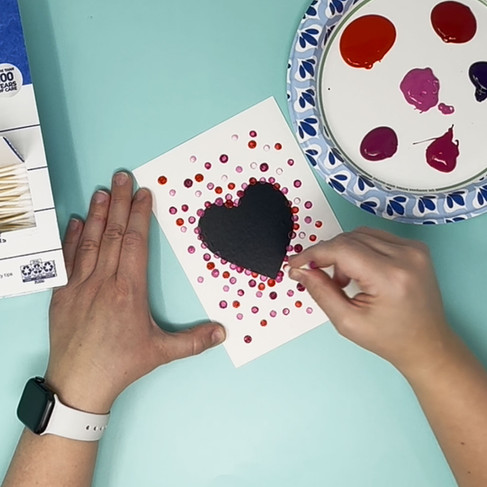 Using Q-tips to place dots of paint on the paper.