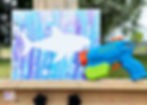Shark painting and water gun sitting on an easel.