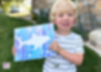 Boy holding completed shark painting.