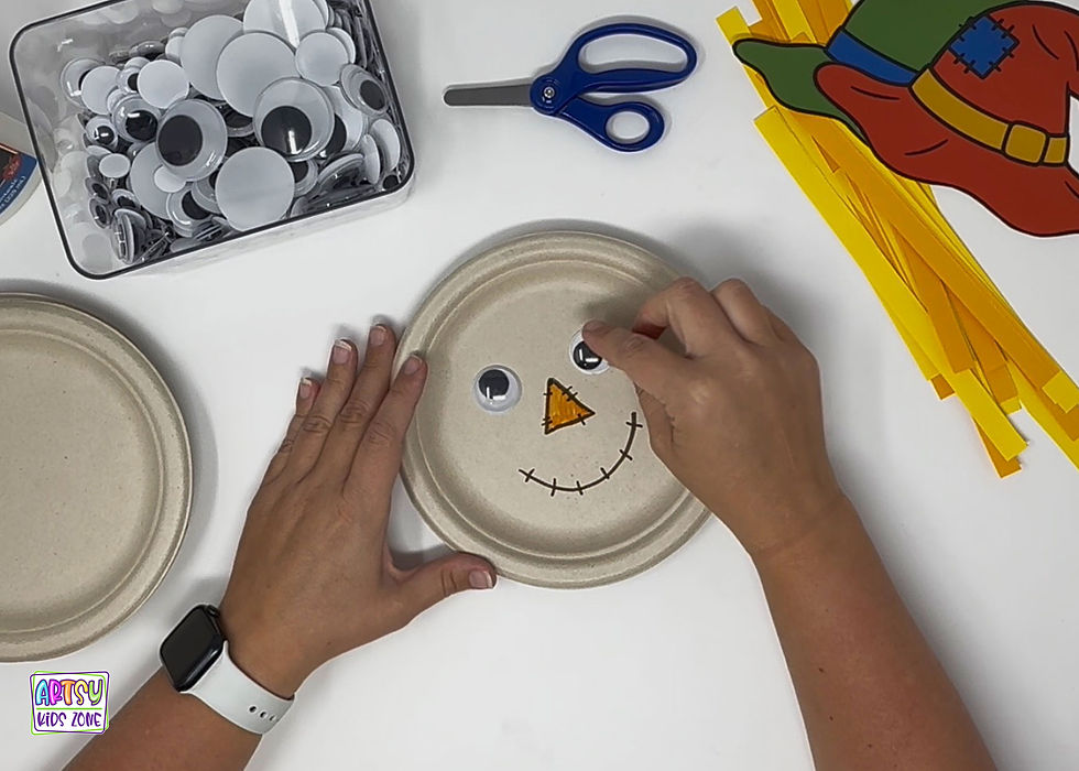 Gluing the eyes on the scarecrow paper plate.