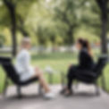 A white female therapist and a young client are sharing a session sitting on two black lo