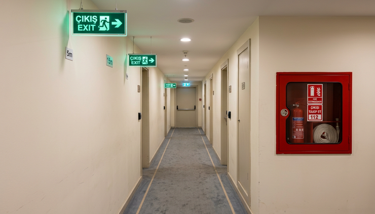 Eye-level view of emergency exit signs along a hotel service corridor