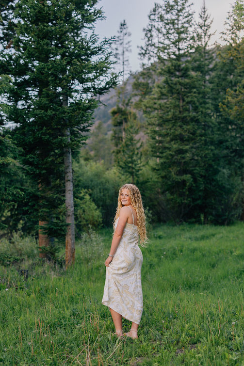 Senior girl standing in a green mountain meadow up the North Fork in Wyoming