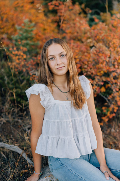 Senior girl posing outdoors with colorful fall leaves in Cody WY