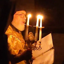 an orthodox bishop carrying lit candles 