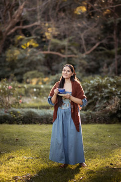 Sunset Woman Photoshoot holding a tea cup in blue dress and brown shawl