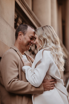 Romantic couple standing close together against historic sandstone architecture during a Sydney CBD photoshoot.