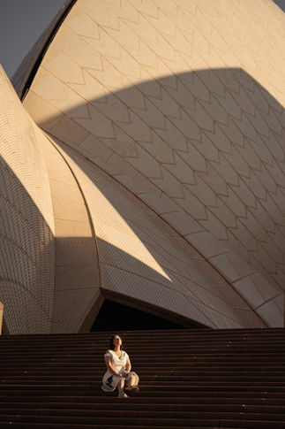 woman sitting at the steps of Sydney Opera House at sunrise