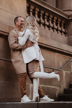 Couple laughing on sandstone steps during a winter couples photoshoot in Sydney CBD.