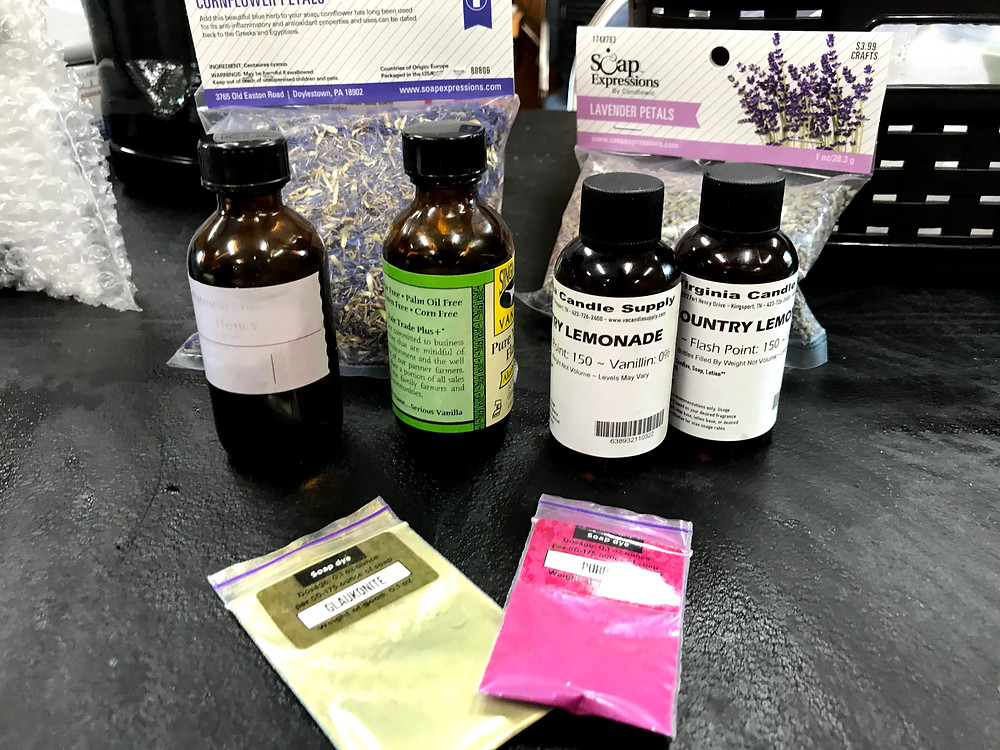Yellow and pink powder, bottles of essential oils, and bags of dried lavender and cornflower petals to mix in our soap.