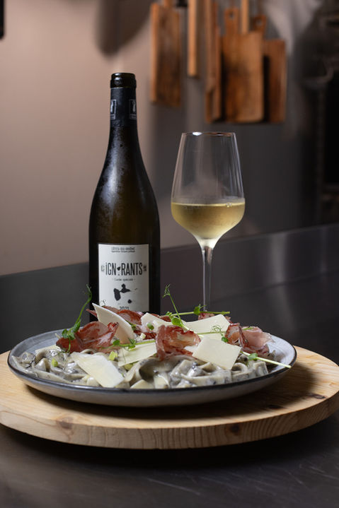 Bouteille de vin "Les Ignorants" accompagnée d'un plat de tagliatelles fraîches, illustrant un accord mets et vin pour une expérience culinaire raffinée.