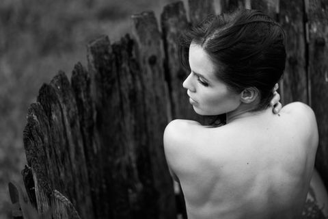 Portrait d'une femme dos nu près d'une clôture