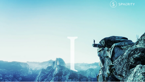 Person standing on a rocky cliff, overlooking a vast mountain landscape. Clear blue sky. Text: "SPHERITY" with a logo.