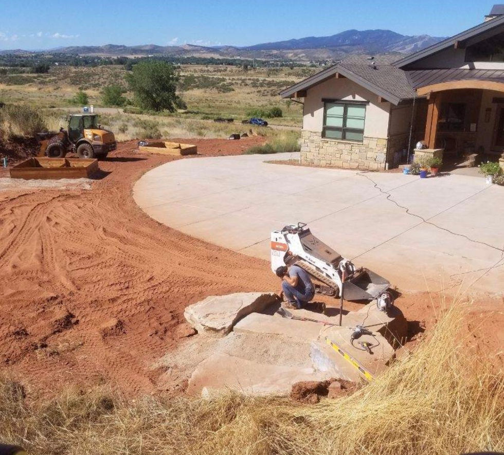 Finished residential landscaping with natural stone, green lawn, trees, pathways, and a modern mountain-style home in Colorado.