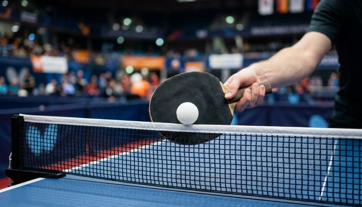 Nærbilde av en bordtennisracket som treffer ballen over nettet