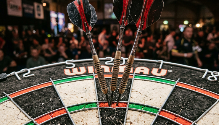 Close-up of three darts grouped around treble 20 on a dartboard