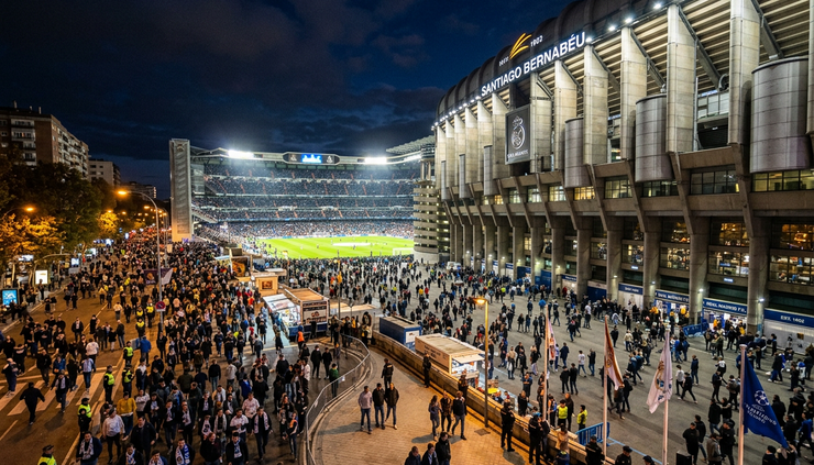 Wide-angle view of a floodlit European football stadium before a night match