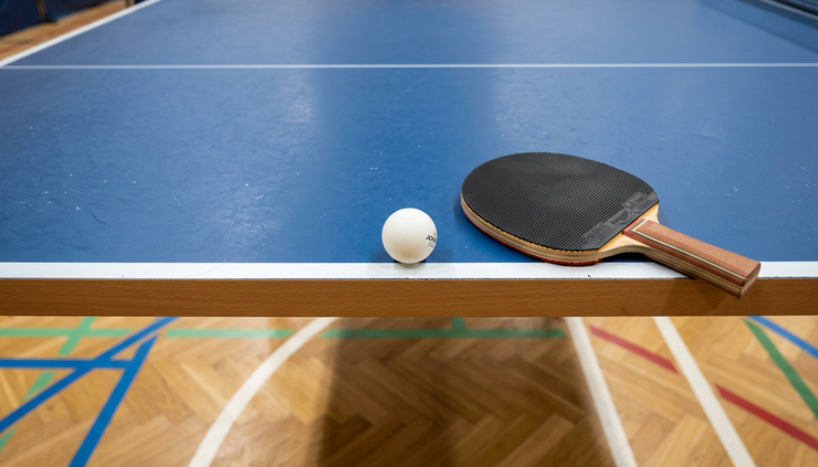 Fugleperspektiv av en bordtennisball på linjen ved siden av en racket
