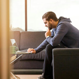 Racquet sports business owner working alone on laptop weighing a difficult decision