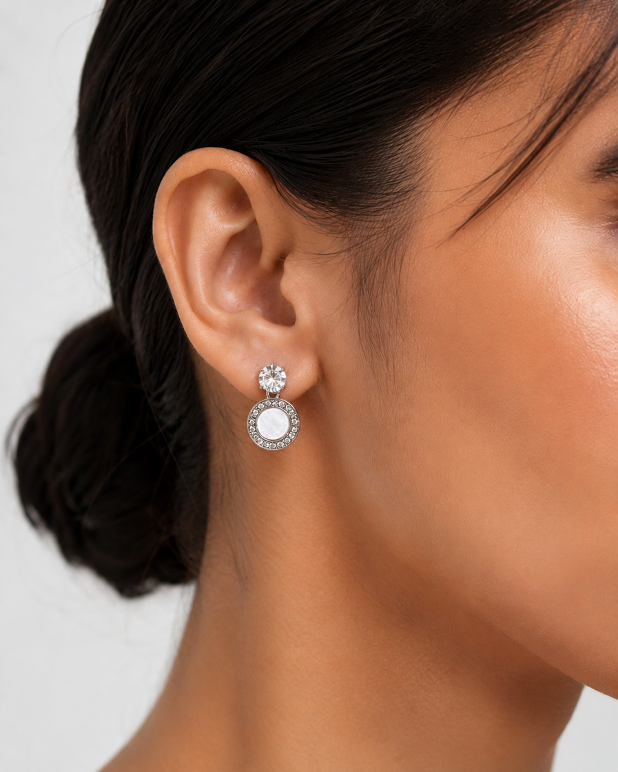 Gold-tone round stud-drop earrings with crystal-style top and pearl-look centre worn by a model.