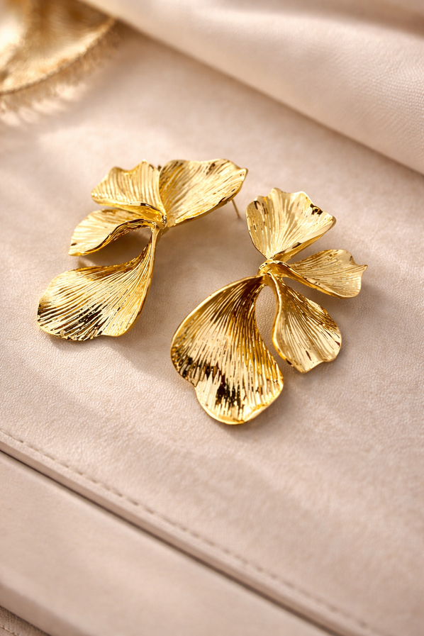 Elegant gold botanical statement earrings on a neutral background