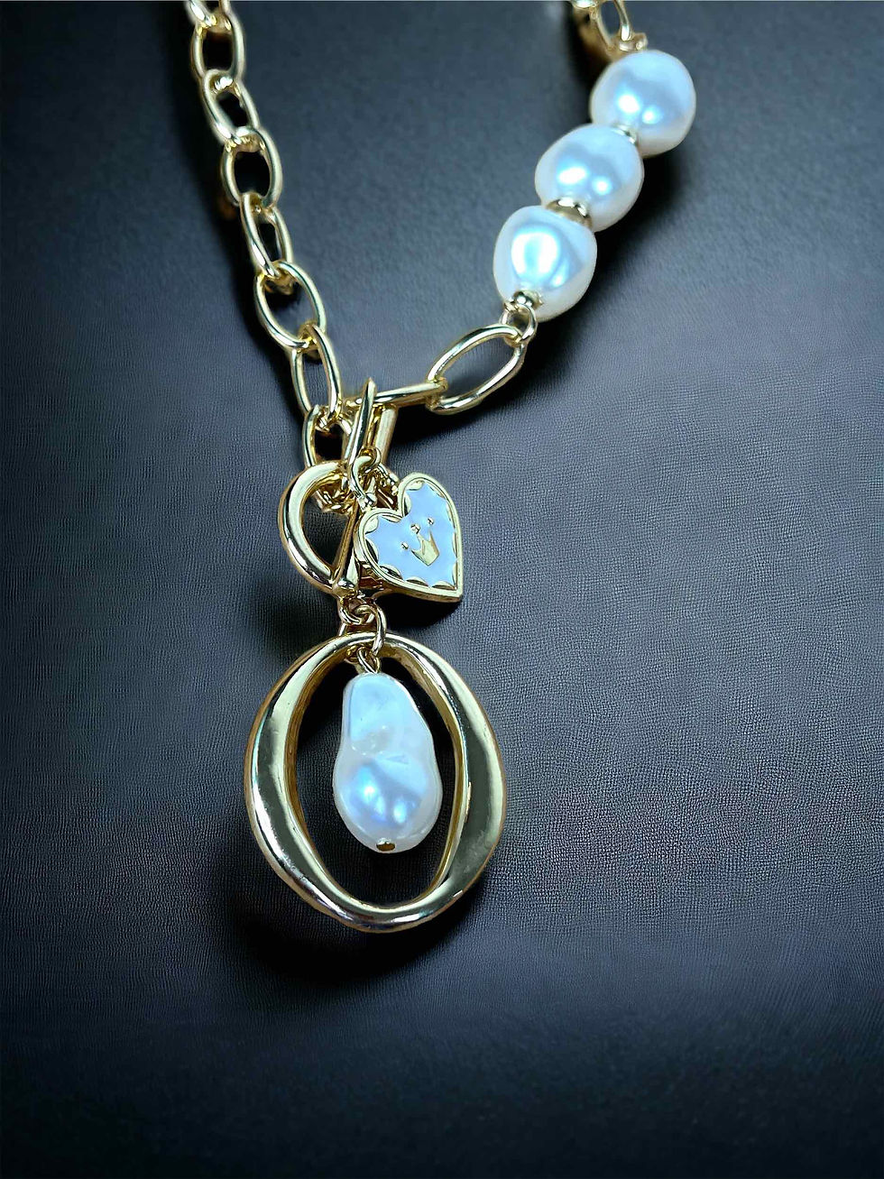 A luxurious 18K gold-plated link chain necklace featuring a heart-shaped charm alongside a shimmering pearl pendant
