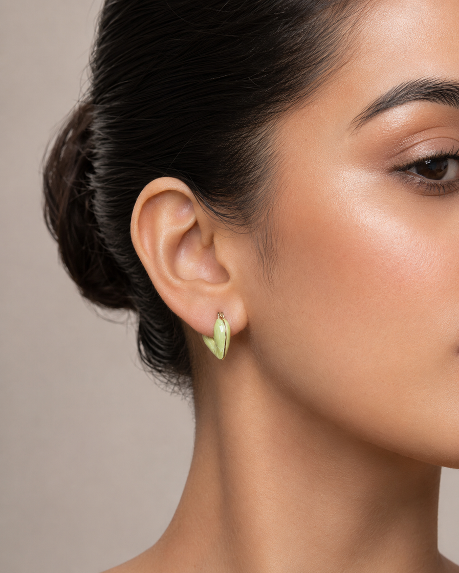 Macro close-up of glossy mint green heart-shaped earring on a model