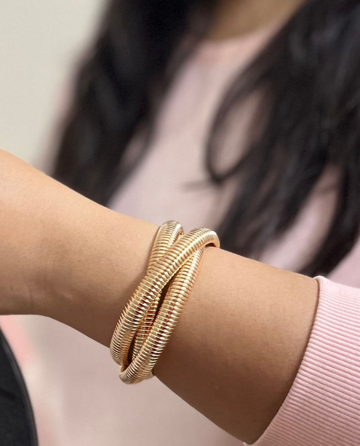 Model wearing modern gold coil bracelet with anti-tarnish plated finish