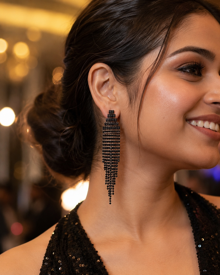 Close-up of long black chandelier earrings styled for a cocktail night