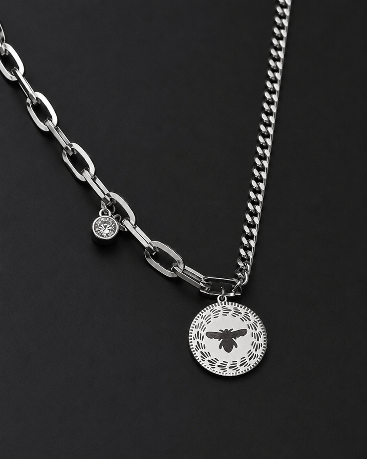 Close-up of round bee motif pendant on a silver stainless steel mixed chain necklace