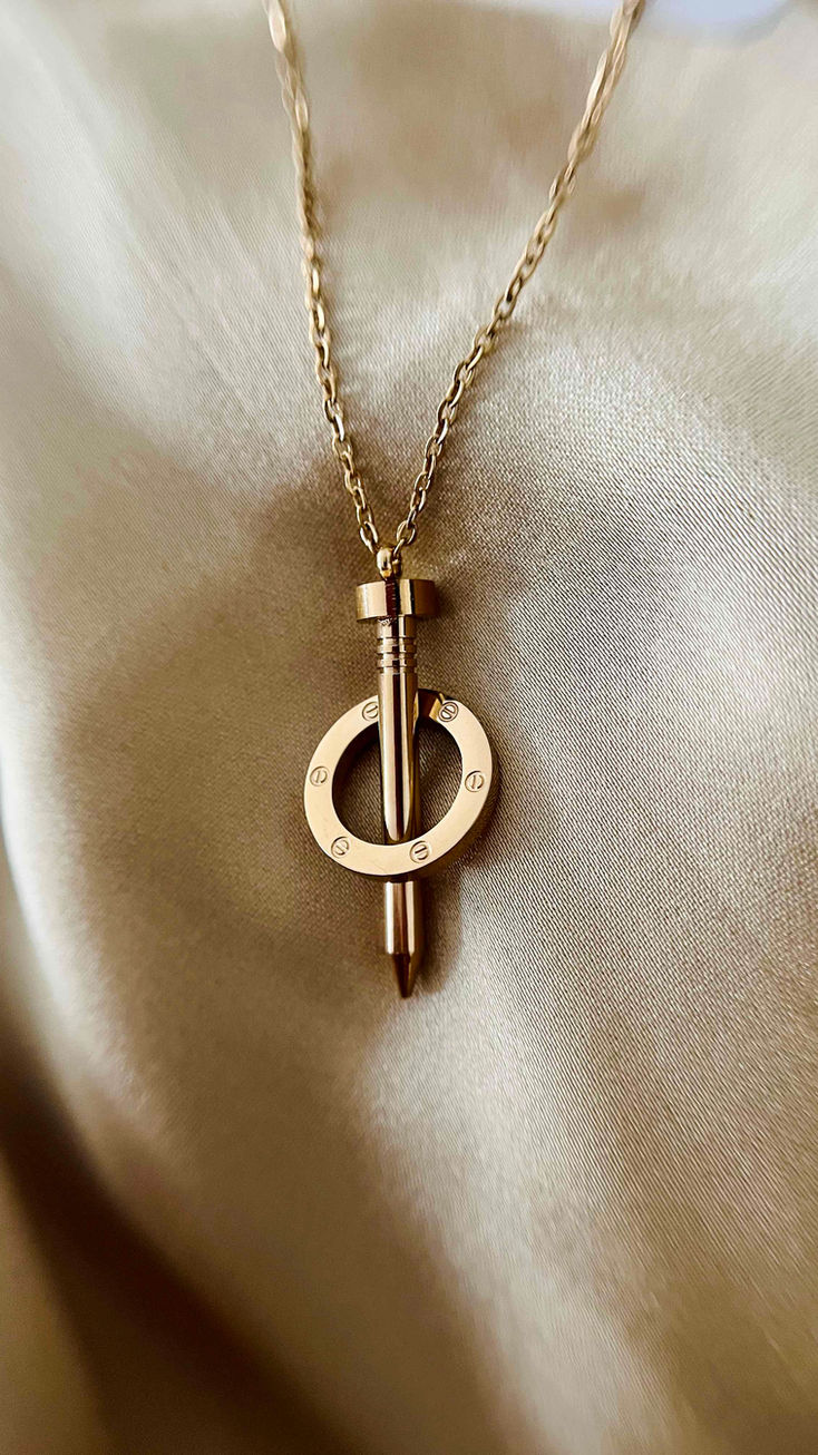 A trendy 18k gold-plated necklace with a nail pendant wrapped by a hoop, blending unconventional design with classic elegance