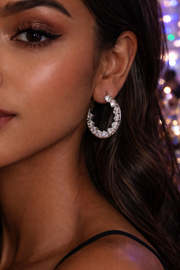 Silver crystal hoop earrings with teardrop stones on black background