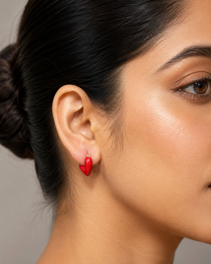 Macro close-up of glossy red heart-shaped earring worn by a model