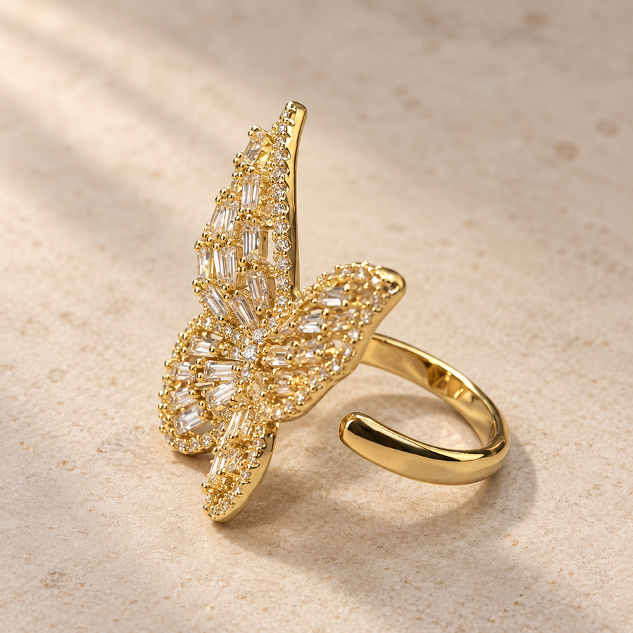 Large gold-tone butterfly ring with clear baguette-style stone detailing and an adjustable open band.