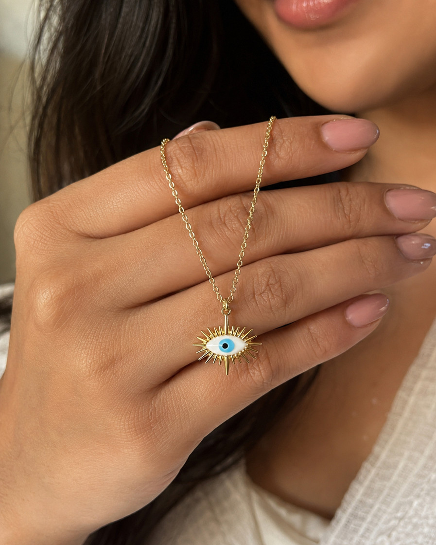 Indian model holding a gold-tone spiked evil eye necklace with a blue nazar centre