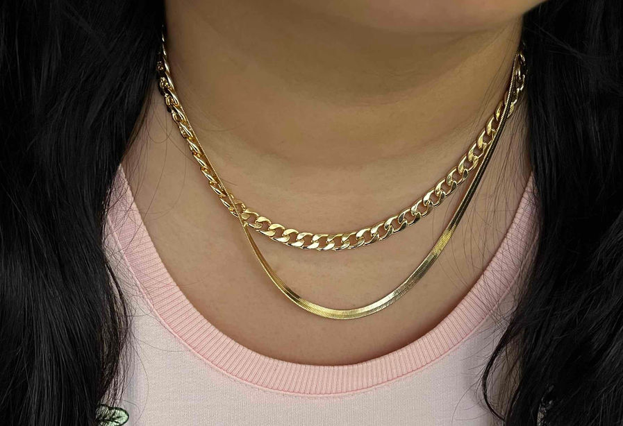 Classic 18K plated Cuban gold chain necklace draped elegantly, showcasing its robust links and lustrous finish against a cont