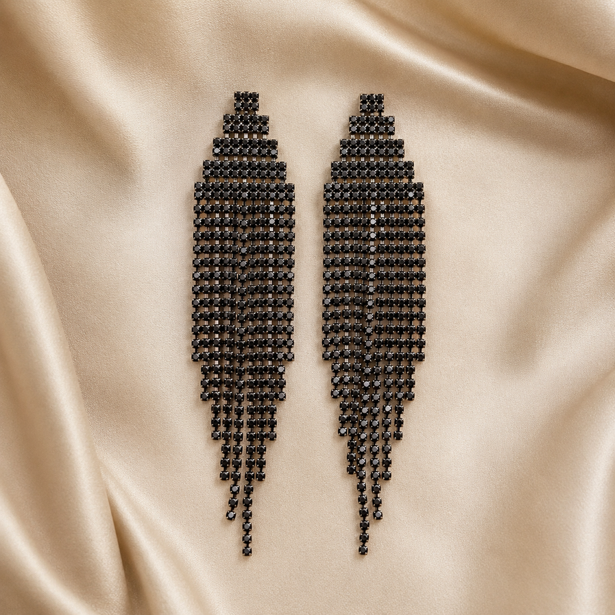 Long black stone chandelier earrings displayed on champagne satin