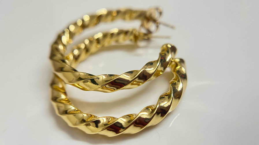 Gold twisted hoop earrings lying on a white surface, showcasing a sophisticated spiral design suitable for daily wear office