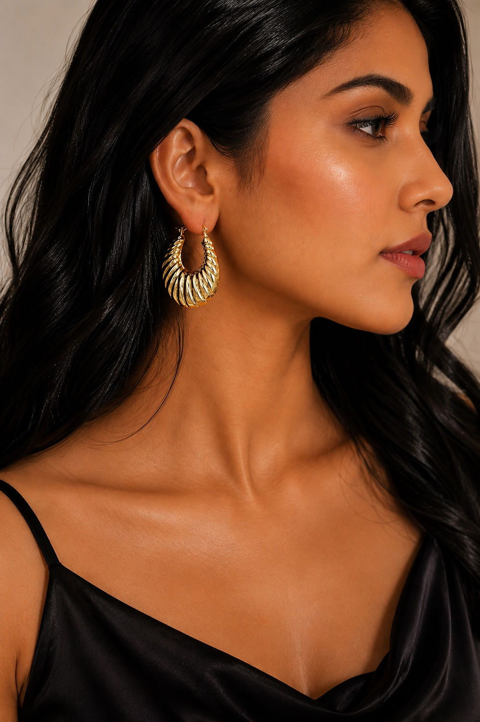 Side profile of woman wearing bold ribbed gold hoop earrings