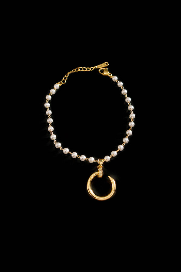 Delicate pearl bracelet with crescent pendant on white background
