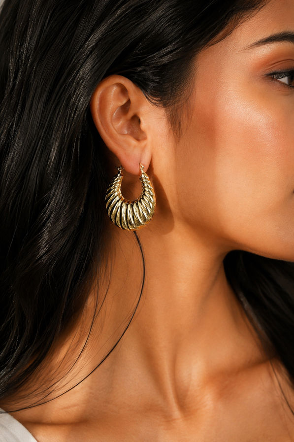 Model wearing ribbed luxe gold hoop earrings with glossy finish