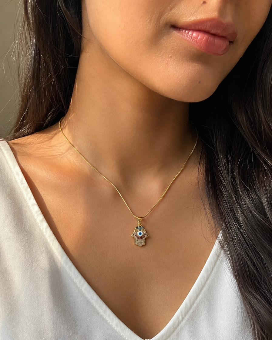 Indian model wearing a small Hamsa evil eye crystal pendant necklace with a gold-tone snake chain