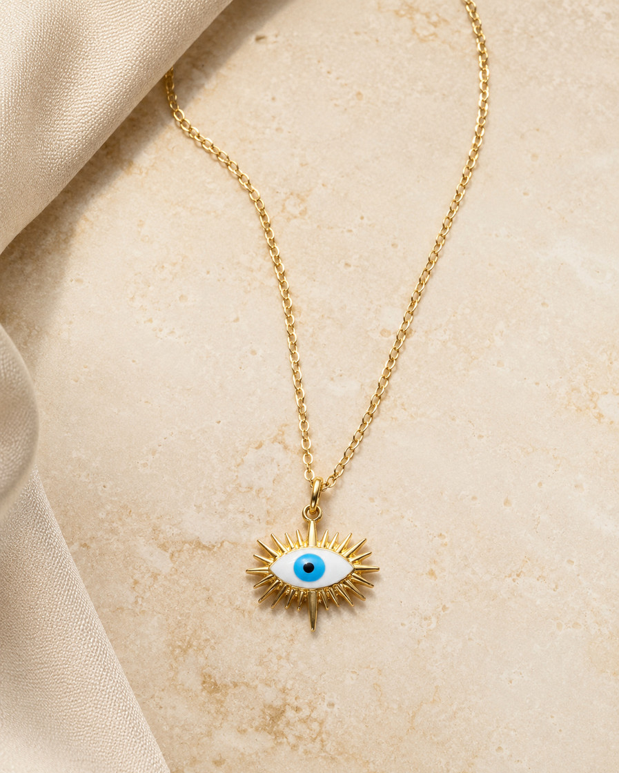 Indian model wearing a gold sunburst evil eye pendant necklace with a delicate link chain