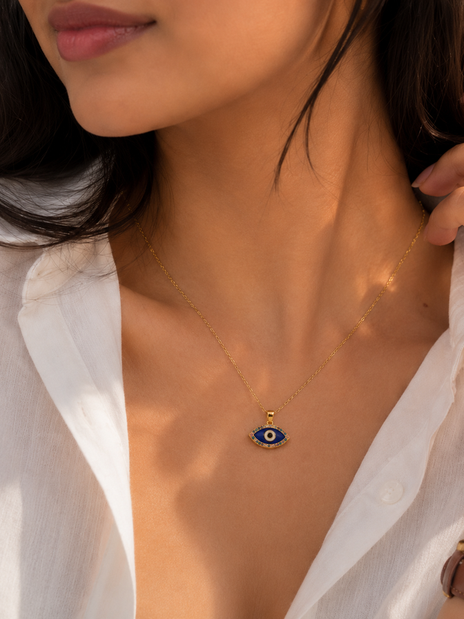 Indian woman wearing a small blue evil eye pendant necklace with a white casual outfit