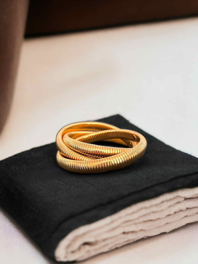 Modern gold plated coil bracelet displayed on black jewellery box