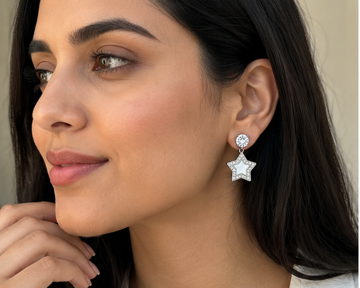 Model wearing silver star stud-drop earrings with crystal-style top and pearl-look star charm
